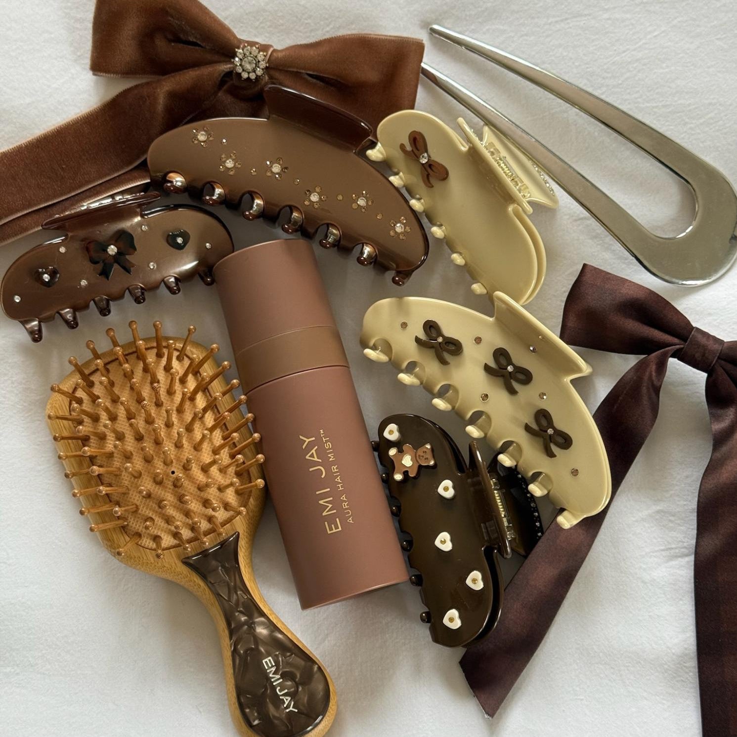 Assorted Emi Jay hair accessories, styling tools, and Aura Hair + Body Mist in Toasted Sugar.