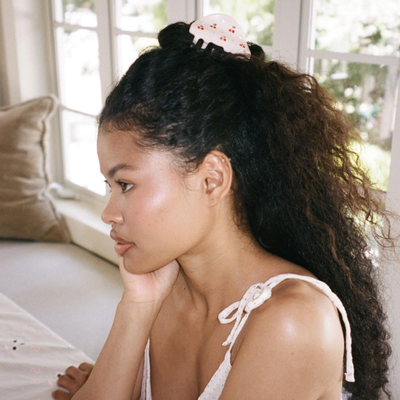 model resting chin in hand wearing Luna Clip in Cherry on Top in hair